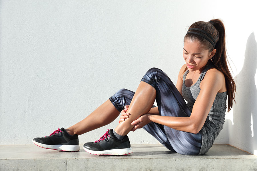 Woman holding her ankle in pain after HYROX training in Singapore - Centurion Orthopaedic Centre